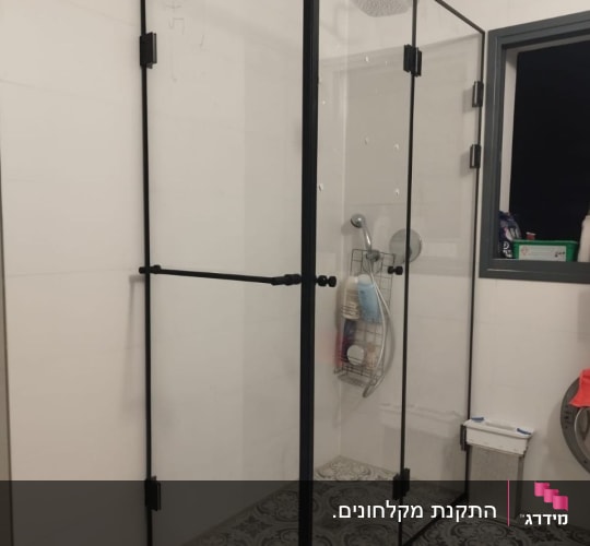 מקלחון זכוכית עם מסגרת שחורה ורצפת אריחים מעוצבת